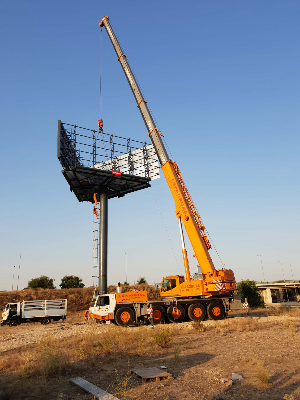 Instalación de un poste publicitario de gran formato con estructura metálica mediante grúa de gran tonelaje, asegurando una colocación segura y precisa para máxima visibilidad.