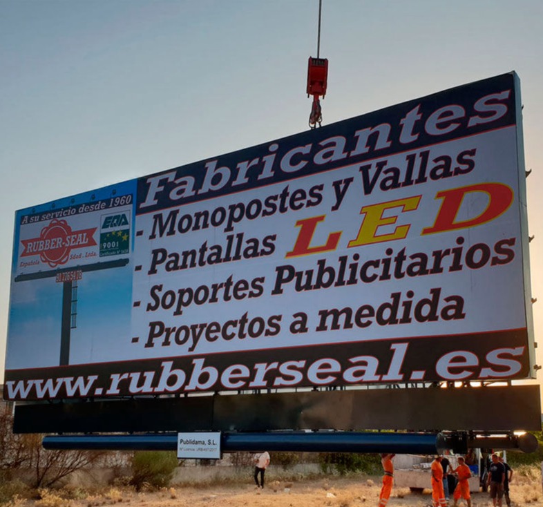 Instalación de una lona publicitaria de gran formato mediante grúa, asegurando una fijación segura y máxima visibilidad.